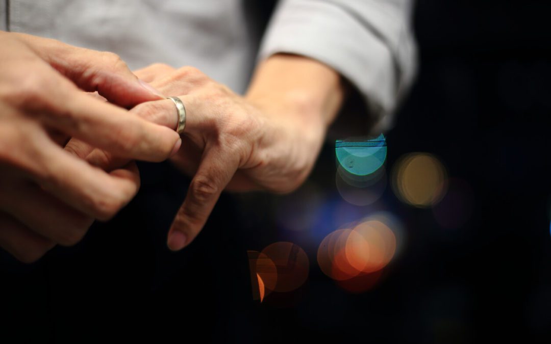 man putting on wedding ring. close up shot of man fidgeting ring with nice out of focus urban light backgrounds.